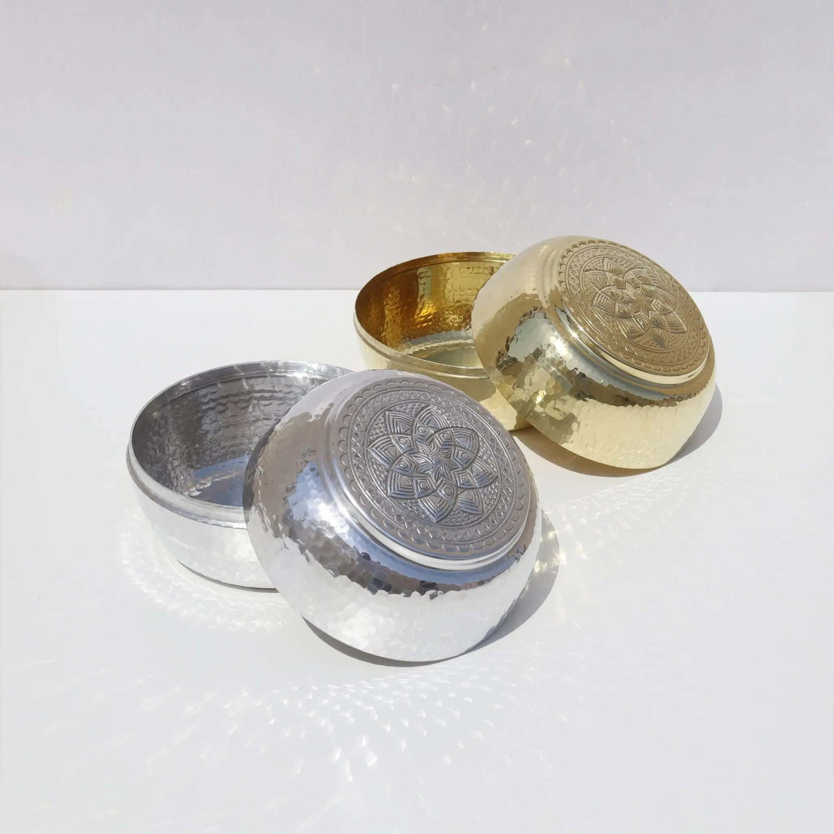 Engraved Silver Box with intricate designs next to a gold box on a white surface, showcasing elegance and craftsmanship.