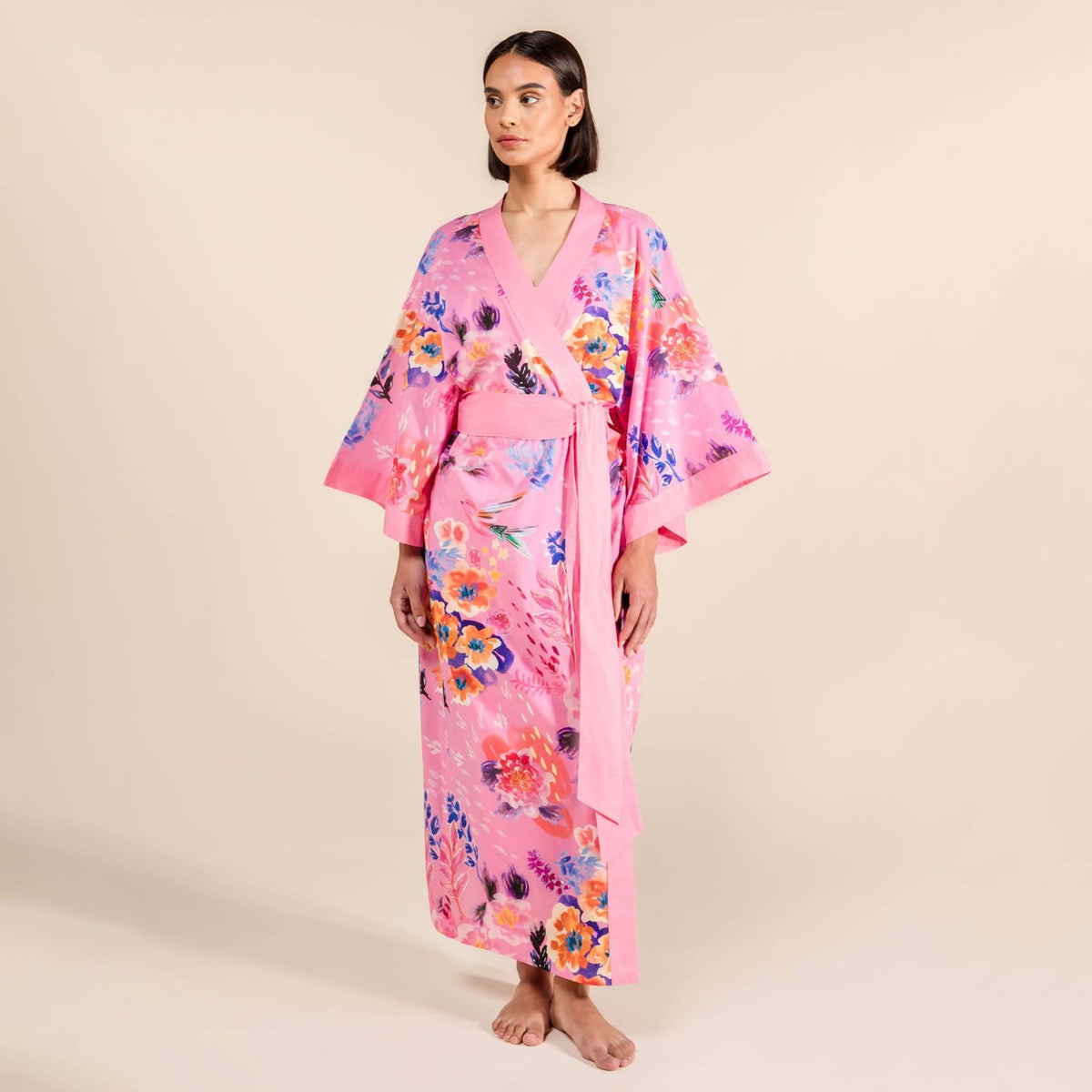 Model wearing a vibrant pink cherry blossom cotton robe with floral patterns, showcasing hibiscus and sacred lotus designs.