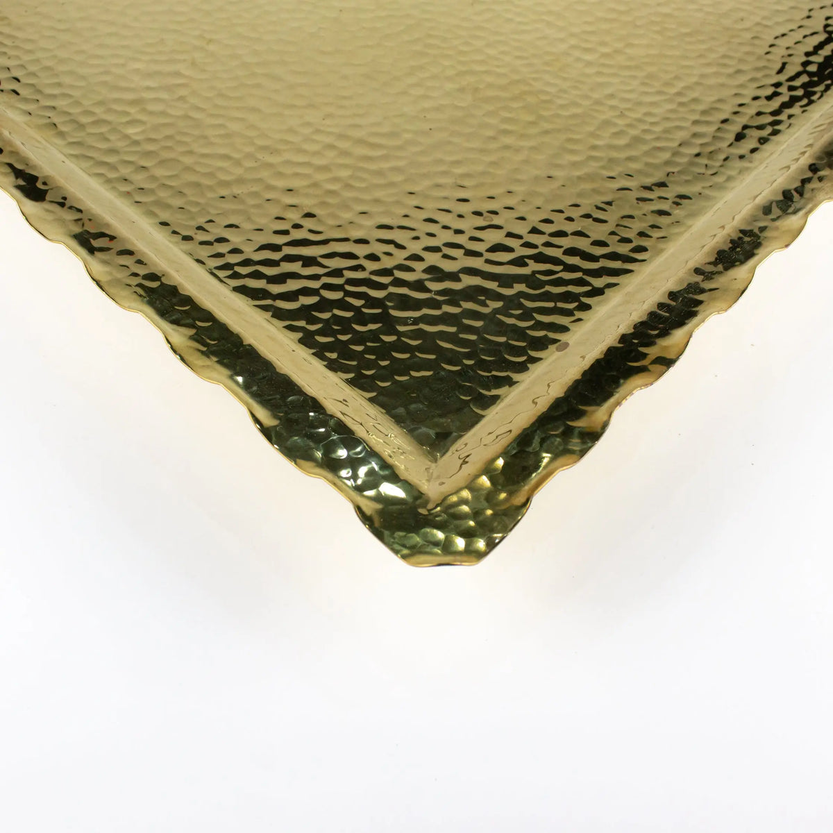 Close-up of a brass zigzag tray with a hammered gold finish and zigzag edges, showcasing its elegant and simplistic design.