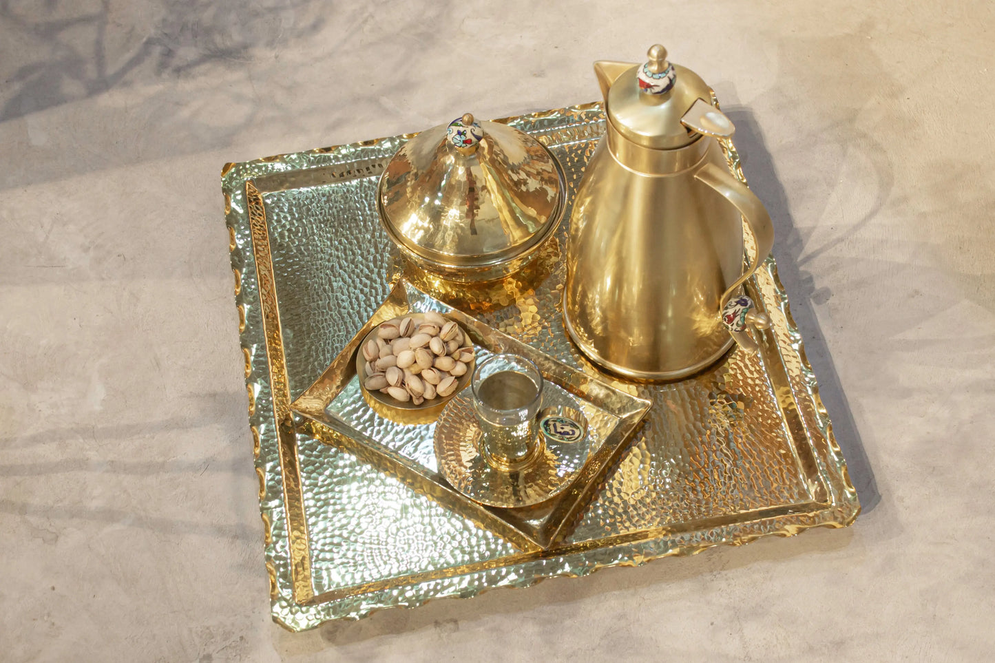 Luxury brass zigzag tray with coffee pot, cups, and nuts, featuring hammered gold finish and intricate design.