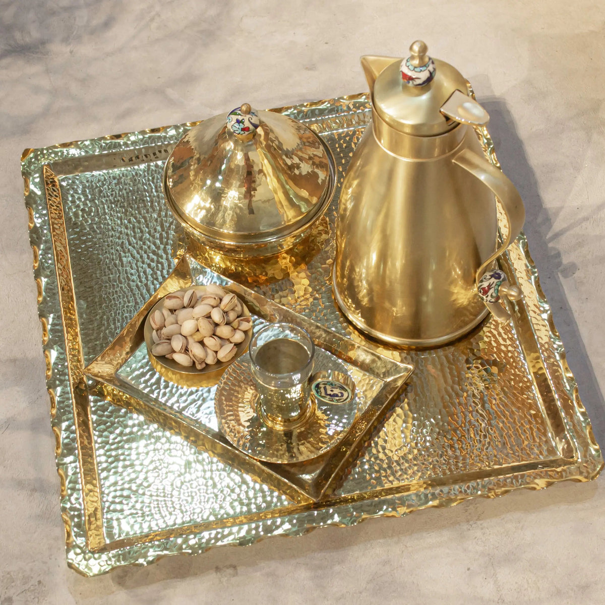 Luxury brass zigzag tray with coffee pot, cups, and nuts, featuring hammered gold finish and intricate design.